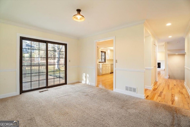 empty room with visible vents, carpet flooring, baseboards, and ornamental molding