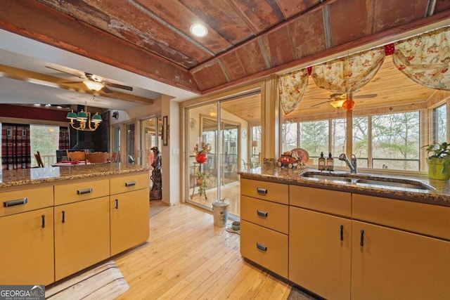 kitchen with stone counters, light wood-style flooring, ceiling fan, a sink, and wood ceiling