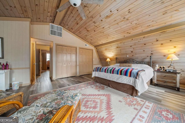 bedroom featuring wood finished floors, visible vents, lofted ceiling, wooden ceiling, and two closets