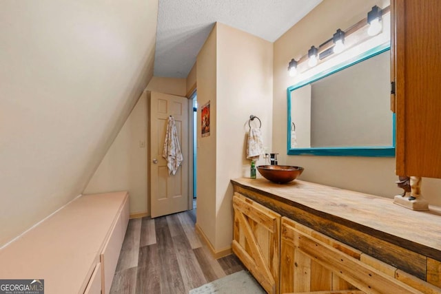 bathroom with vanity, wood finished floors, and a textured ceiling