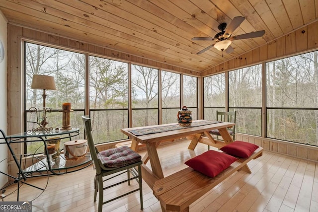 sunroom / solarium featuring plenty of natural light, wooden ceiling, a ceiling fan, and vaulted ceiling