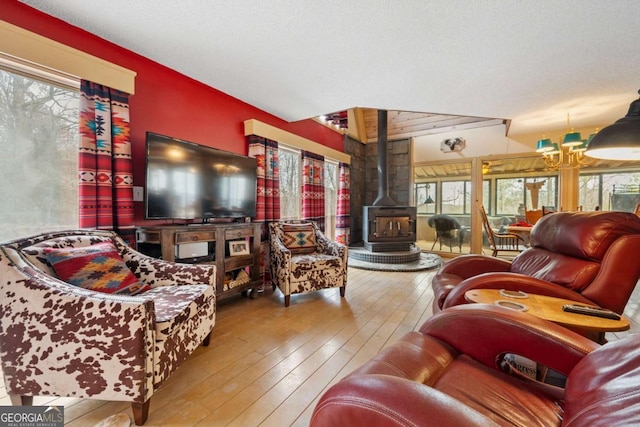 living area with an inviting chandelier, hardwood / wood-style floors, and a wood stove