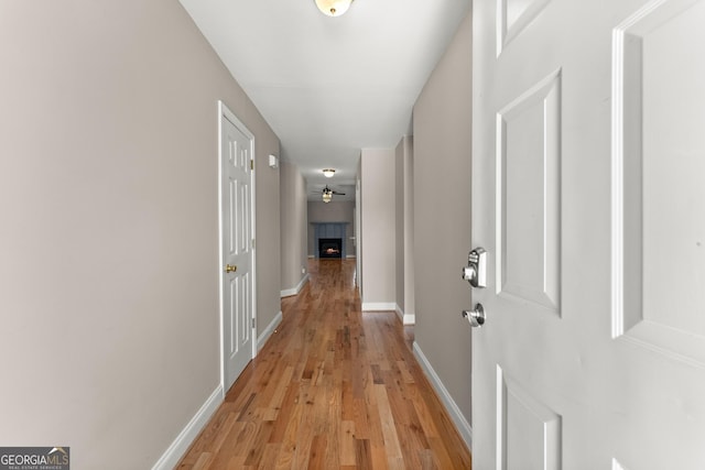 corridor with baseboards and light wood-type flooring