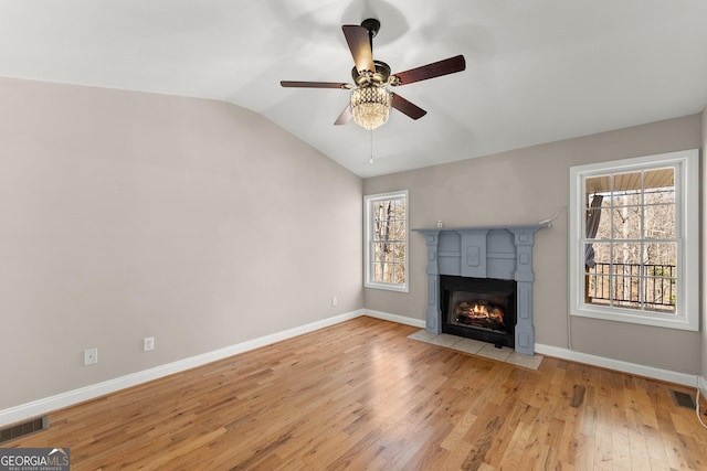 unfurnished living room with a wealth of natural light, visible vents, lofted ceiling, and wood finished floors