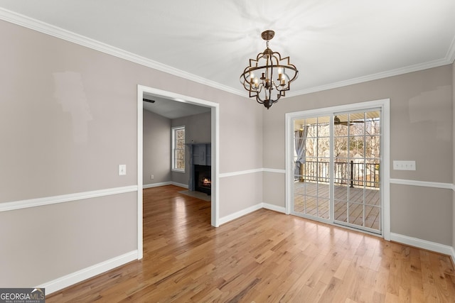 unfurnished dining area with crown molding, baseboards, a fireplace with flush hearth, light wood-style floors, and a notable chandelier