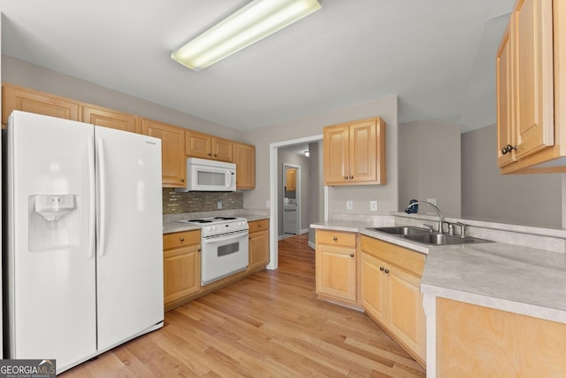 kitchen with light brown cabinetry, light countertops, light wood-type flooring, white appliances, and a sink
