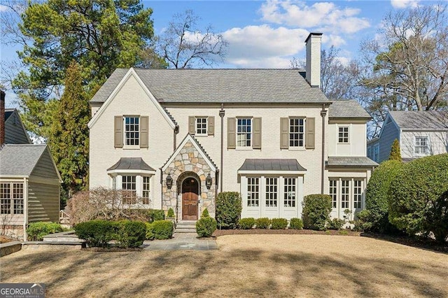 view of front of house featuring stone siding, brick siding, and a chimney