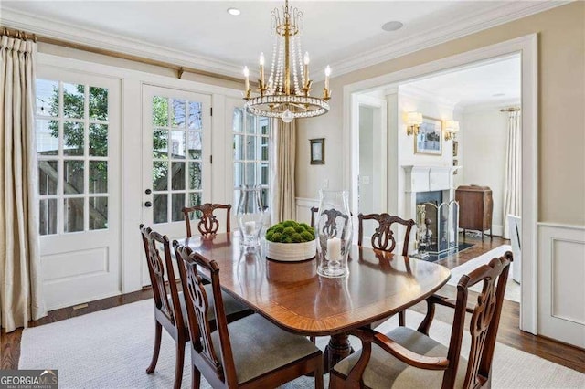 dining room featuring ornamental molding, wainscoting, an inviting chandelier, wood finished floors, and a decorative wall