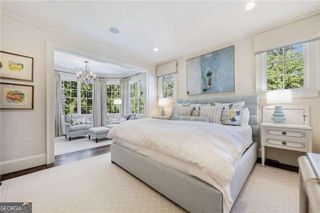 bedroom featuring ornamental molding, multiple windows, light wood-type flooring, and a chandelier