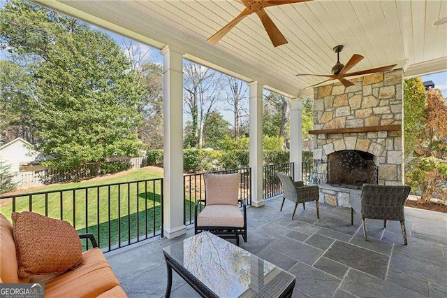 sunroom / solarium featuring wooden ceiling, an outdoor stone fireplace, and ceiling fan