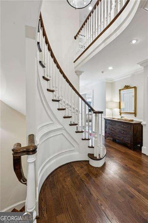 staircase featuring crown molding, baseboards, recessed lighting, a high ceiling, and wood finished floors