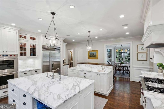 kitchen featuring a center island with sink, stainless steel appliances, crown molding, and a sink