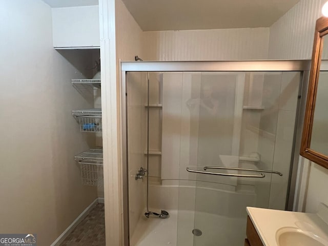 full bathroom featuring vanity, baseboards, and a shower with door