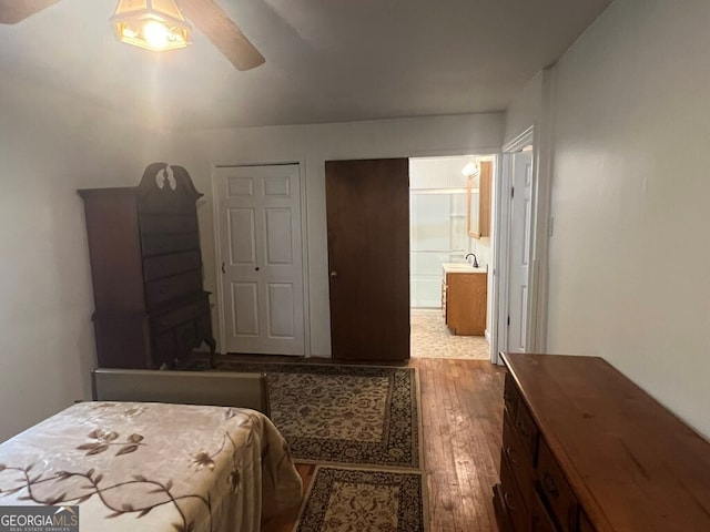 bedroom featuring a sink, ensuite bath, ceiling fan, and hardwood / wood-style flooring