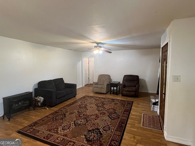 living room featuring baseboards, a ceiling fan, and wood finished floors