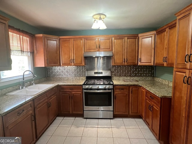 kitchen with range hood, brown cabinetry, a sink, decorative backsplash, and gas range