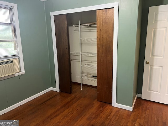 unfurnished bedroom featuring cooling unit, a closet, baseboards, and wood finished floors