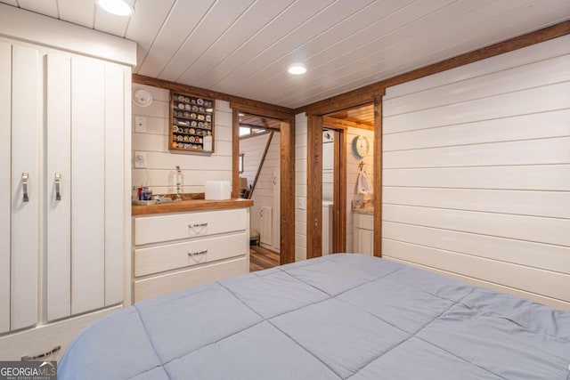 bedroom with wet bar, wooden walls, and recessed lighting