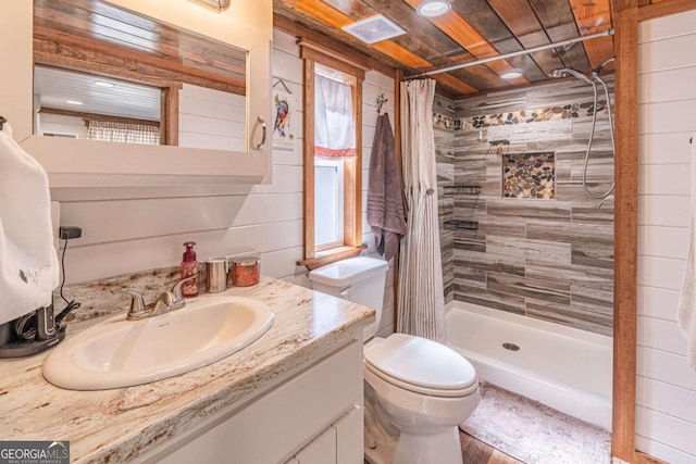 bathroom with visible vents, toilet, tiled shower, and vanity