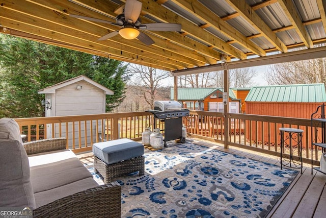 deck featuring an outbuilding, a ceiling fan, a shed, and a grill