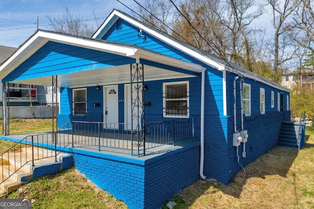 view of front of home with a porch, brick siding, and a front yard