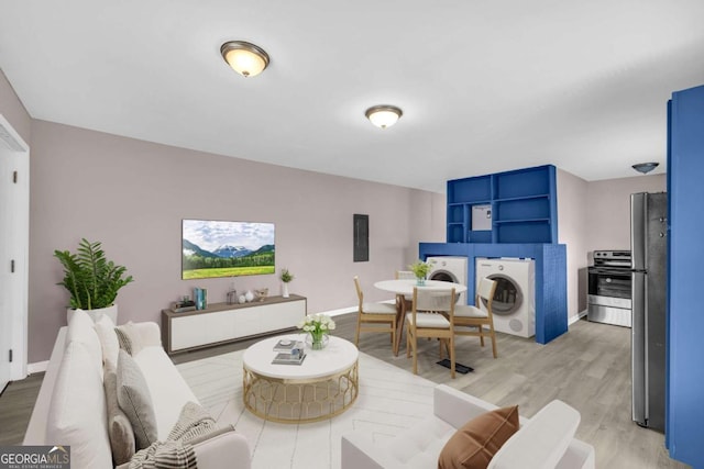 living area featuring independent washer and dryer, light wood-type flooring, and baseboards