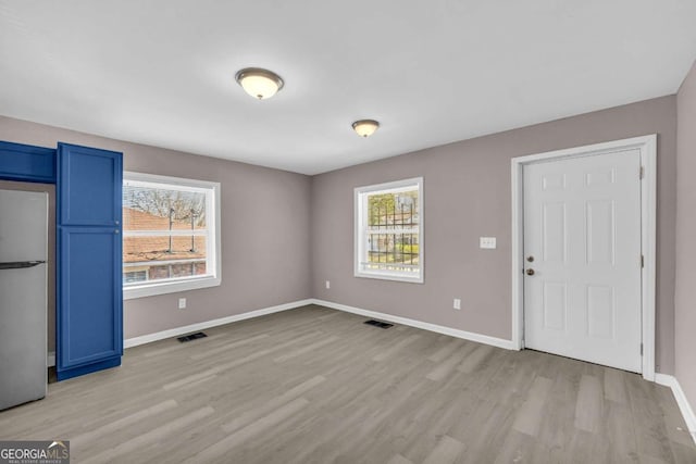 interior space featuring visible vents, light wood-style flooring, and baseboards