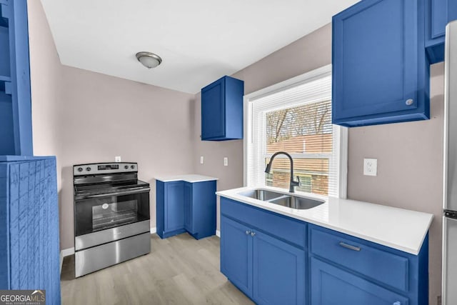 kitchen featuring light wood finished floors, blue cabinetry, stainless steel electric range oven, and a sink