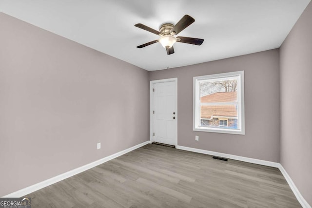 empty room with visible vents, ceiling fan, baseboards, and wood finished floors