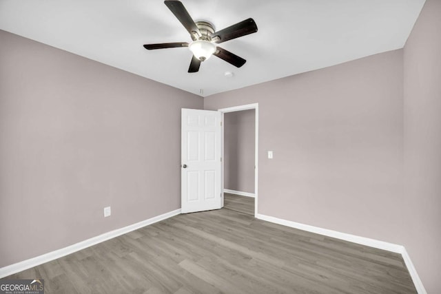 unfurnished room featuring a ceiling fan, baseboards, and wood finished floors