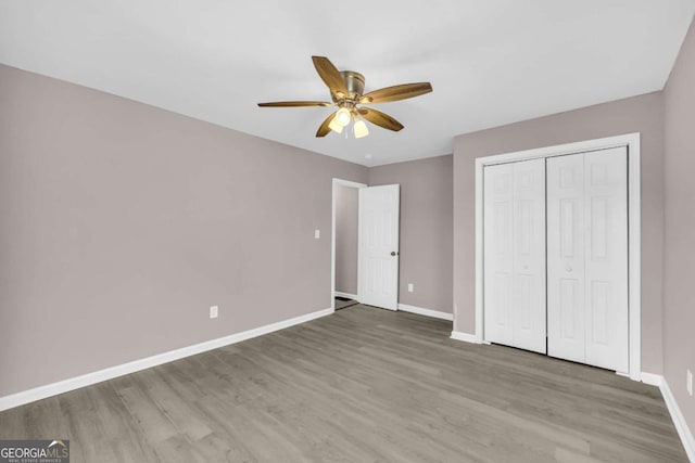 unfurnished bedroom with a closet, baseboards, wood finished floors, and a ceiling fan