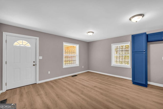 foyer entrance featuring visible vents, baseboards, and light wood finished floors