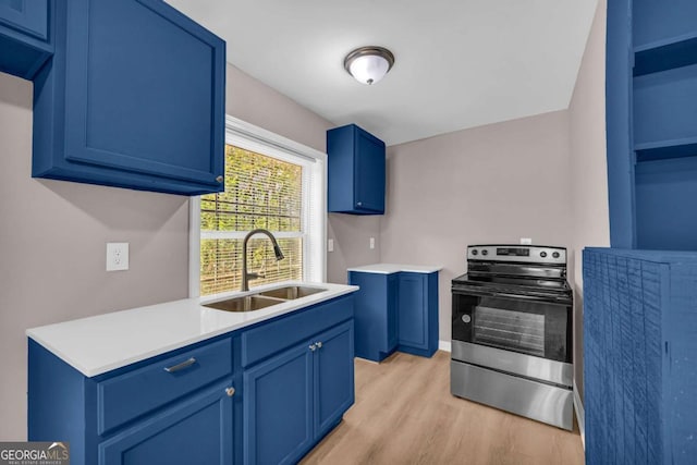 kitchen featuring light wood finished floors, blue cabinetry, a sink, stainless steel range with electric cooktop, and light countertops