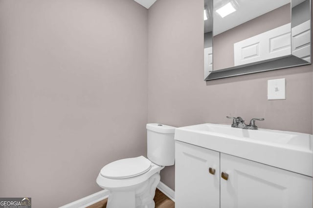 bathroom with vanity, toilet, wood finished floors, and baseboards