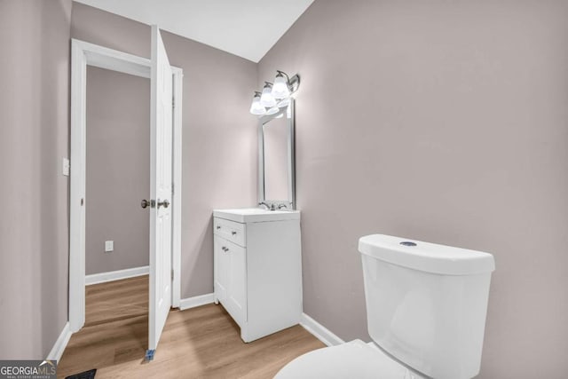 bathroom with toilet, vanity, baseboards, and wood finished floors