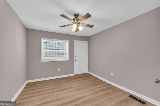 unfurnished room featuring light wood-style flooring, baseboards, visible vents, and ceiling fan