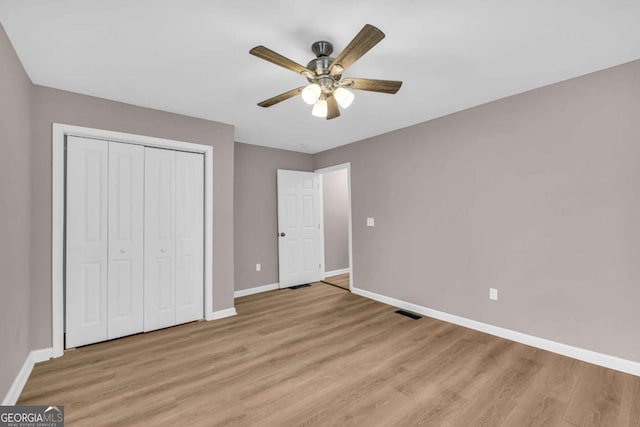 unfurnished bedroom with light wood-style flooring, baseboards, and a closet