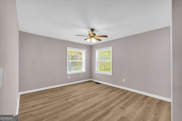 unfurnished room with visible vents, ceiling fan, baseboards, and wood finished floors