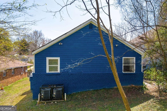 view of home's exterior featuring brick siding, a yard, and central AC