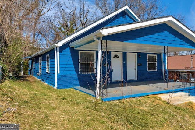 view of front of home featuring brick siding, a patio area, and a front lawn