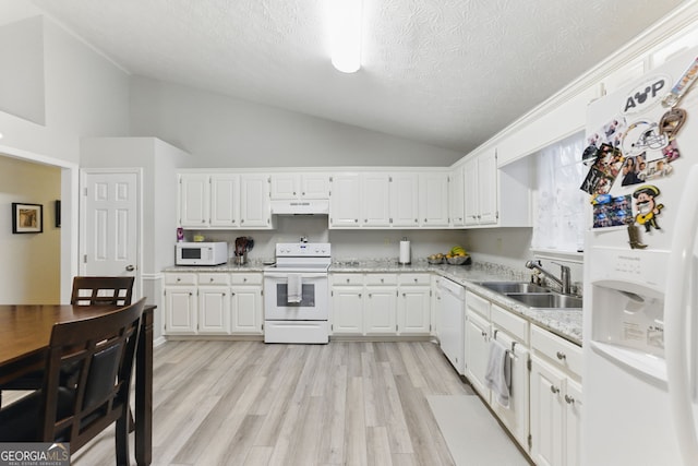 kitchen featuring white appliances, a sink, vaulted ceiling, white cabinets, and under cabinet range hood