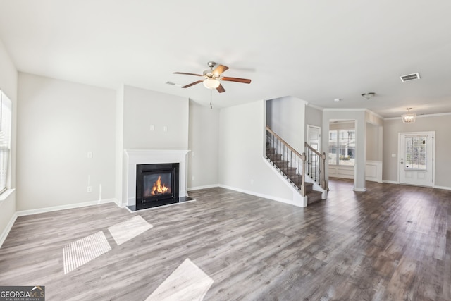 7783 Hansel Ln, Lithonia, GA 30058 - unfurnished living room with stairs, a glass covered fireplace, wood finished floors, ceiling fan, and ornamental molding