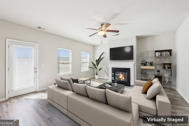 7783 Hansel Ln, Lithonia, GA 30058 - living room with baseboards, a glass covered fireplace, a ceiling fan, and wood finished floors