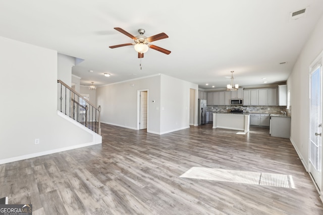 7783 Hansel Ln, Lithonia, GA 30058 - unfurnished living room featuring a chandelier, a ceiling fan, stairway, wood finished floors, and baseboards