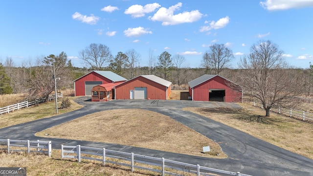 view of front facade featuring an outbuilding, fence, a pole building, and aphalt driveway