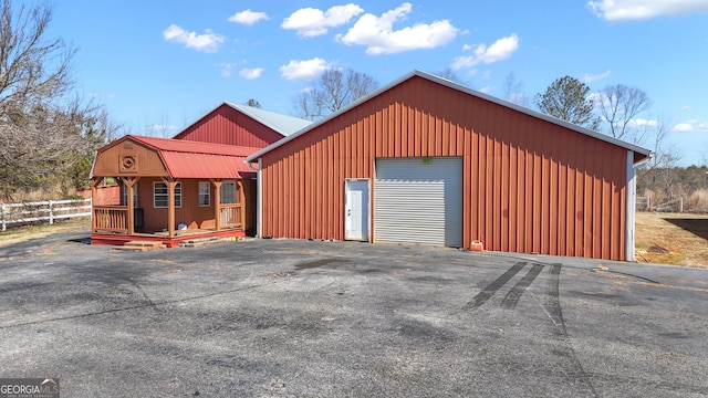 view of outdoor structure featuring an outbuilding, fence, and driveway