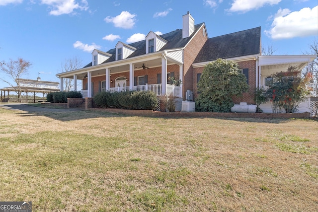 exterior space featuring a yard, brick siding, covered porch, and a chimney