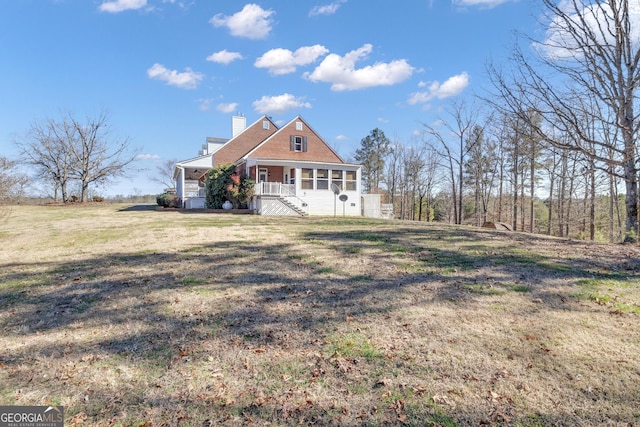 view of front of house featuring a front yard, a porch, a sunroom, and a chimney