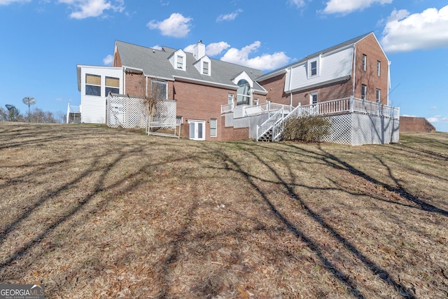 rear view of house featuring brick siding, stairway, a lawn, and a wooden deck