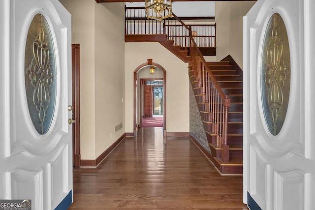 entrance foyer featuring baseboards, arched walkways, wood finished floors, and stairs